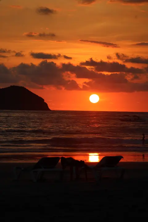 Sunset over the Pacific Ocean with an island on the horizon