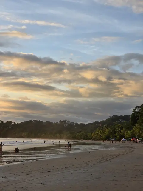 Clouds at dusk over the beach and forested hills